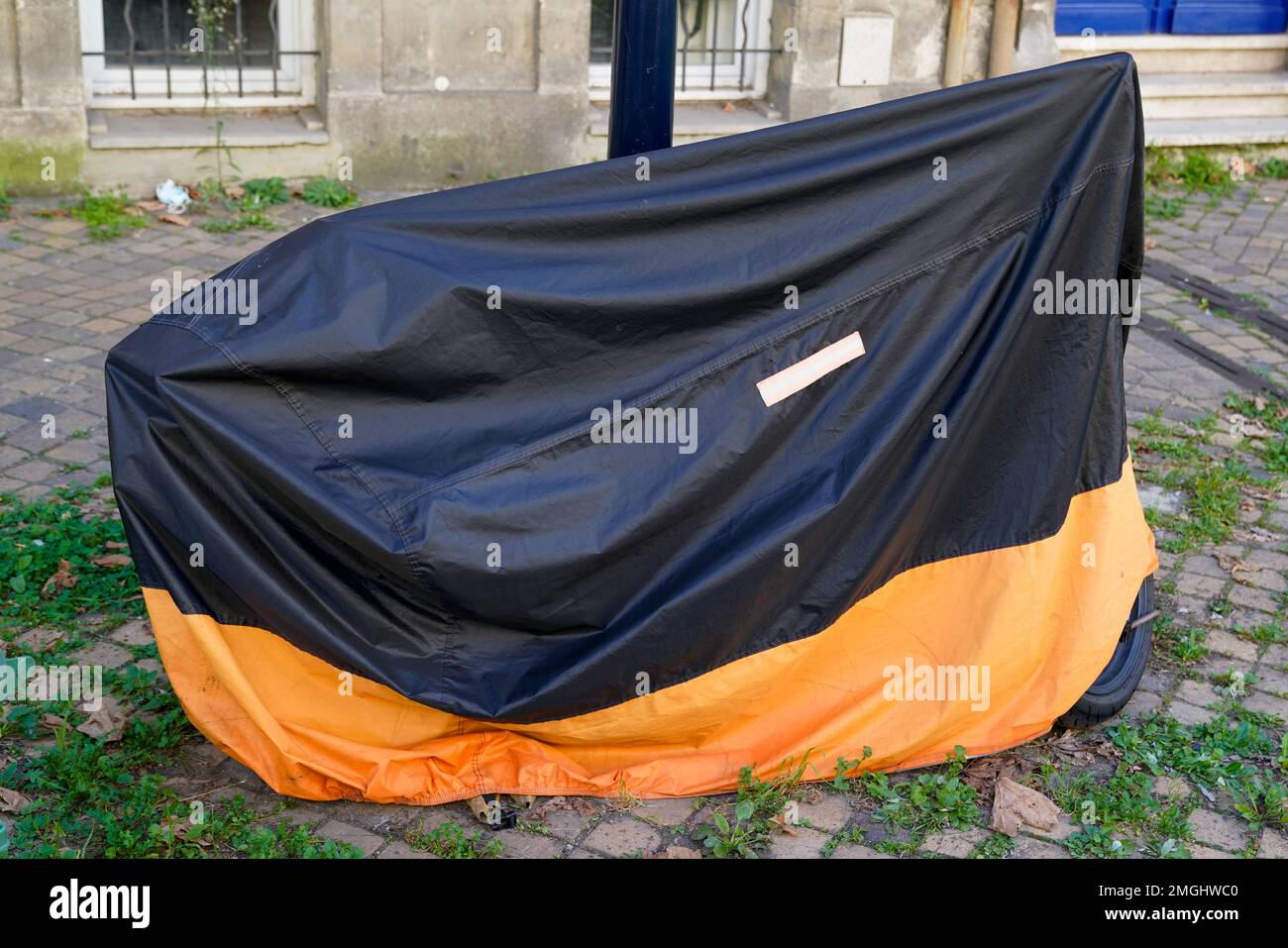 moto protegida por la cubierta de plástico protectora naranja y negro de la  bicicleta en la ciudad de la calle de la motocicleta con la chaqueta de la  lona Fotografía de stock -
