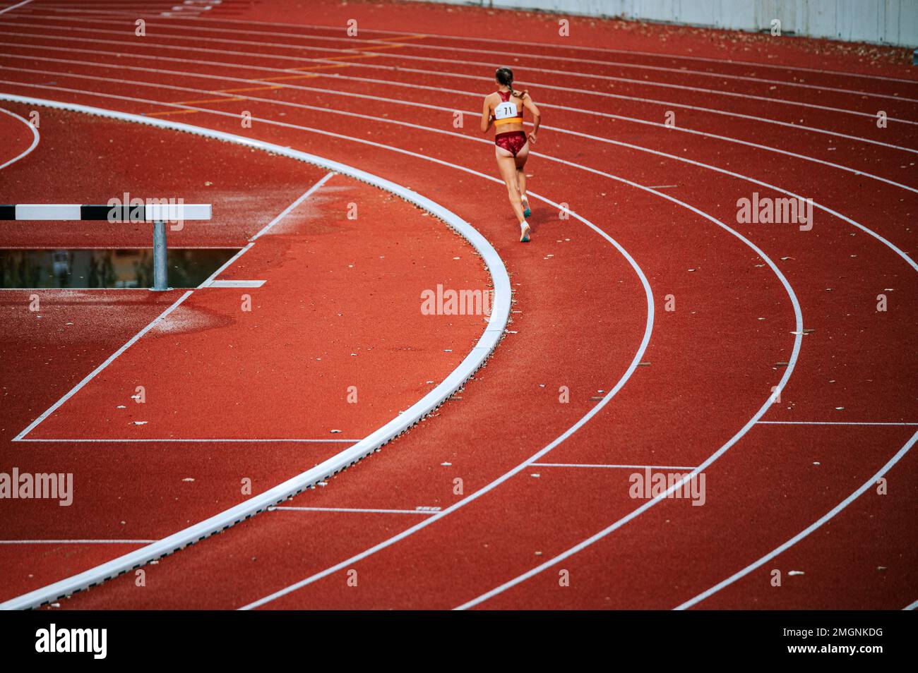 Atleta femenina enfocada empujando sus límites en una carrera de distancia en la pista. Adecuado para campañas deportivas y fitness, destacando determinación y perseverancia Foto de stock