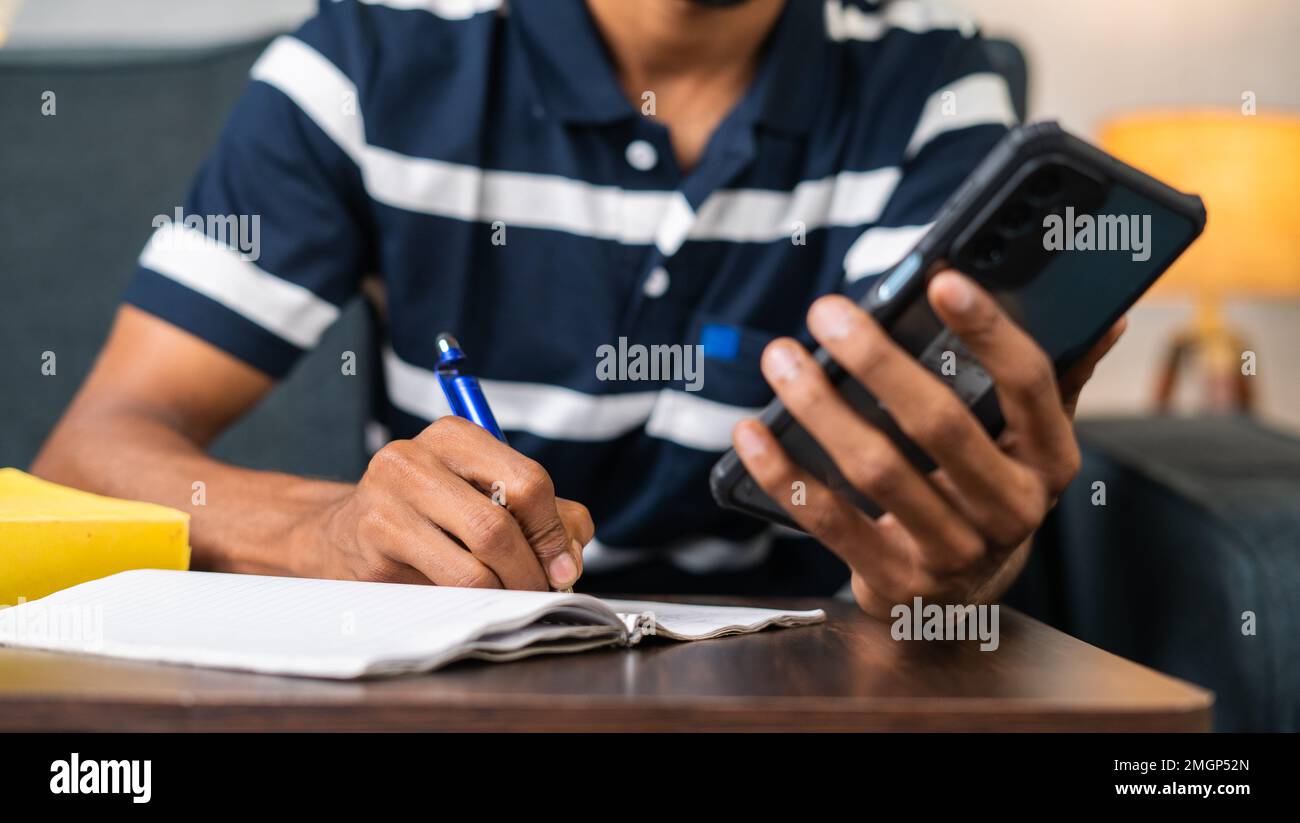 Primer plano de manos escribiendo notas desde el teléfono móvil en casa - concepto de e-learning, tecnología y educación Foto de stock