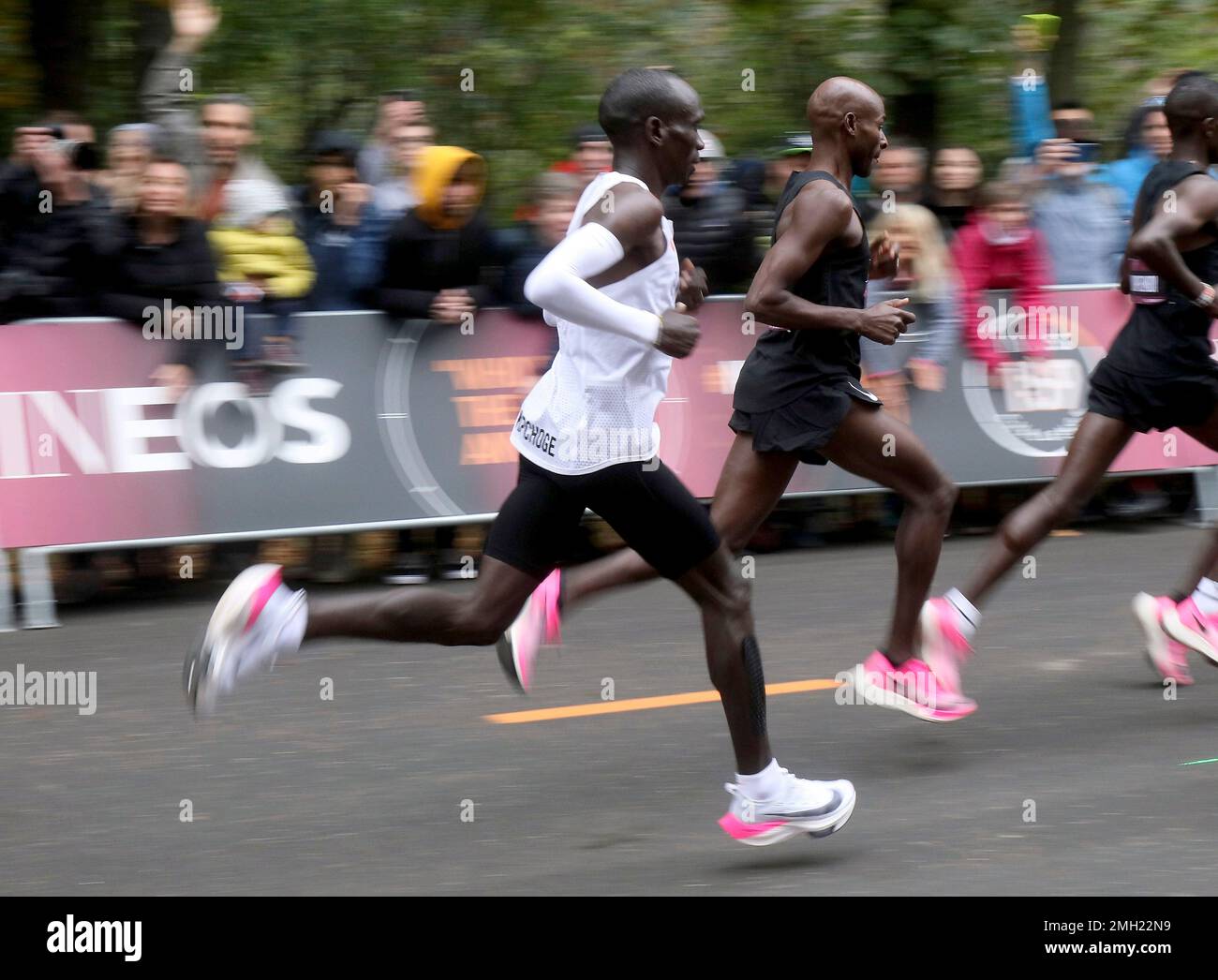 In this Oct. 12, 2019 photo, marathon runner Eliud Kipchoge from Kenya,  white vest, wearing Nike AlphaFly prototype running shoe, and his  pacemaking team, wearing pink Nike Vaporfly shoes, run during the