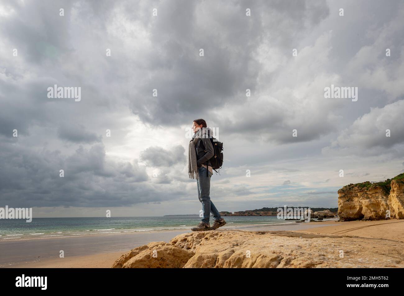 Mujer excursionista de pie en una roca mirando al océano. Foto de stock