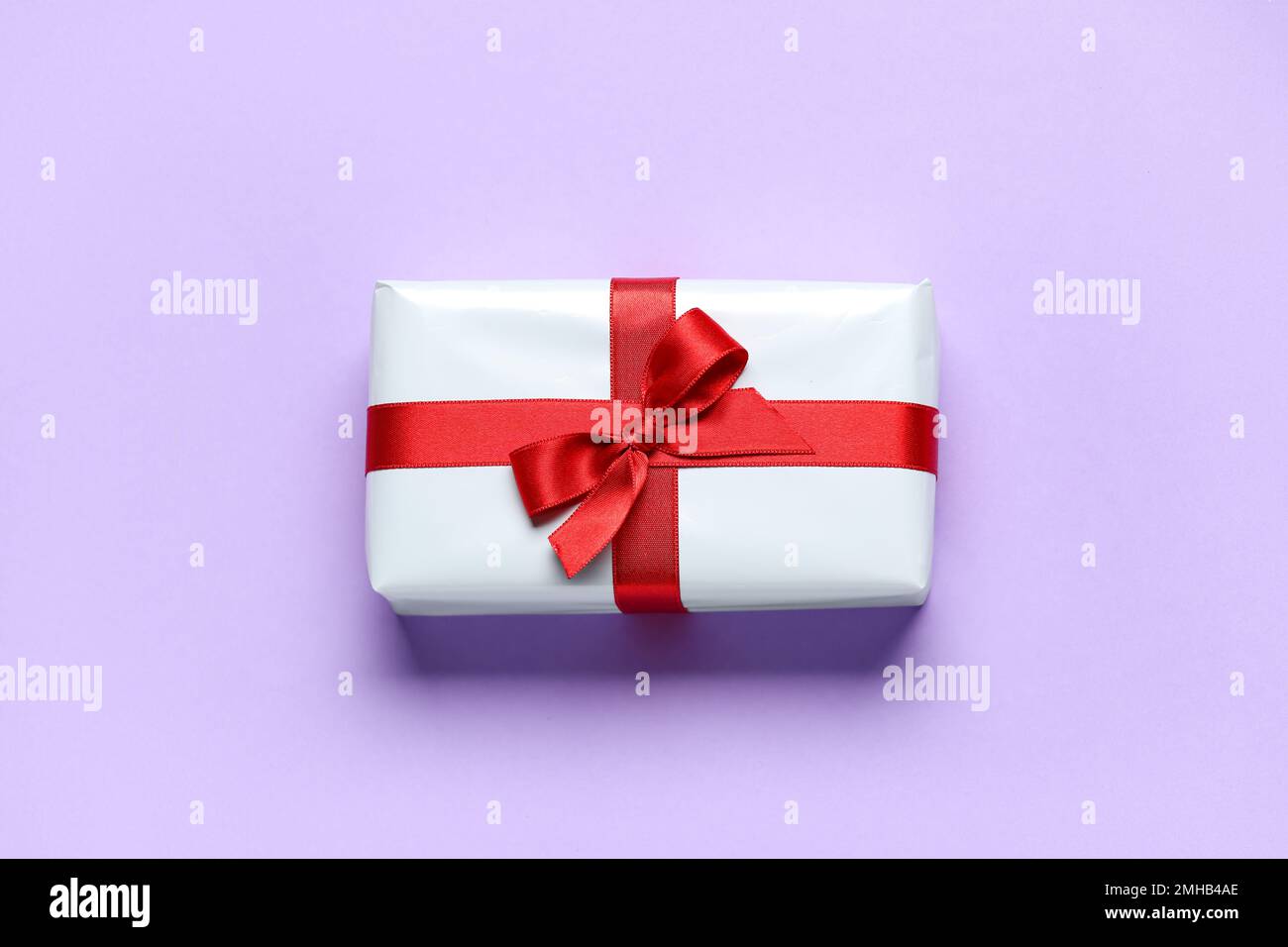 Caja de regalo con hermoso arco sobre fondo lila. Celebración del Día de  San Valentín Fotografía de stock - Alamy