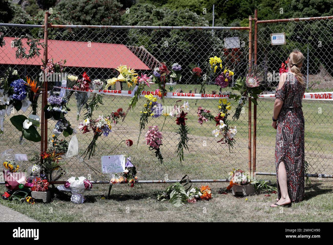 A woman places flowers on a fence at the waterfront in Whakatane, New