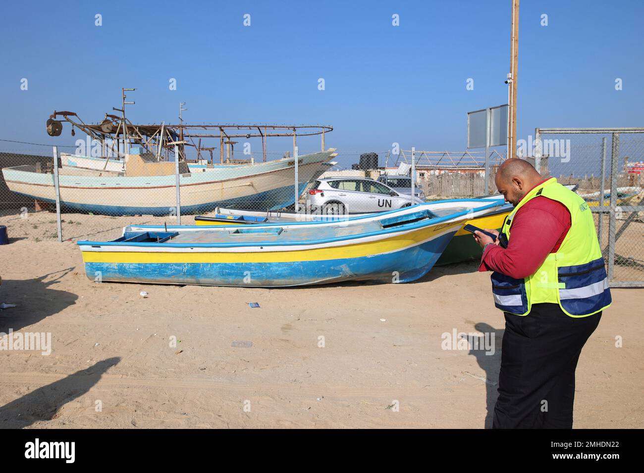 Un empleado de la ONU se encuentra cerca de un barco de pesca después de  instalar un nuevo motor en el puerto marítimo de Gaza en la ciudad de Gaza.  En la