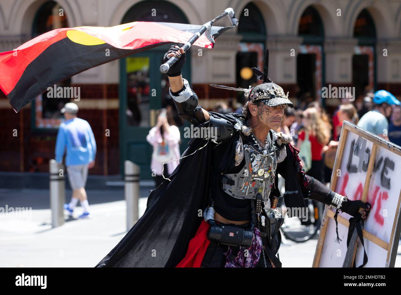 Melbourne, Australia, 26 de enero de 2023. Un activista indígena vestido con un elaborado traje es visto girando una bandera aborigen durante la protesta anual del Día de la Invasión en Melbourne, organizada por los indígenas australianos y sus aliados, pide el fin de la celebración del Día de Australia y el reconocimiento de la Soberanía Indígena. Crédito: Dave Hewison/Alamy Live News Foto de stock