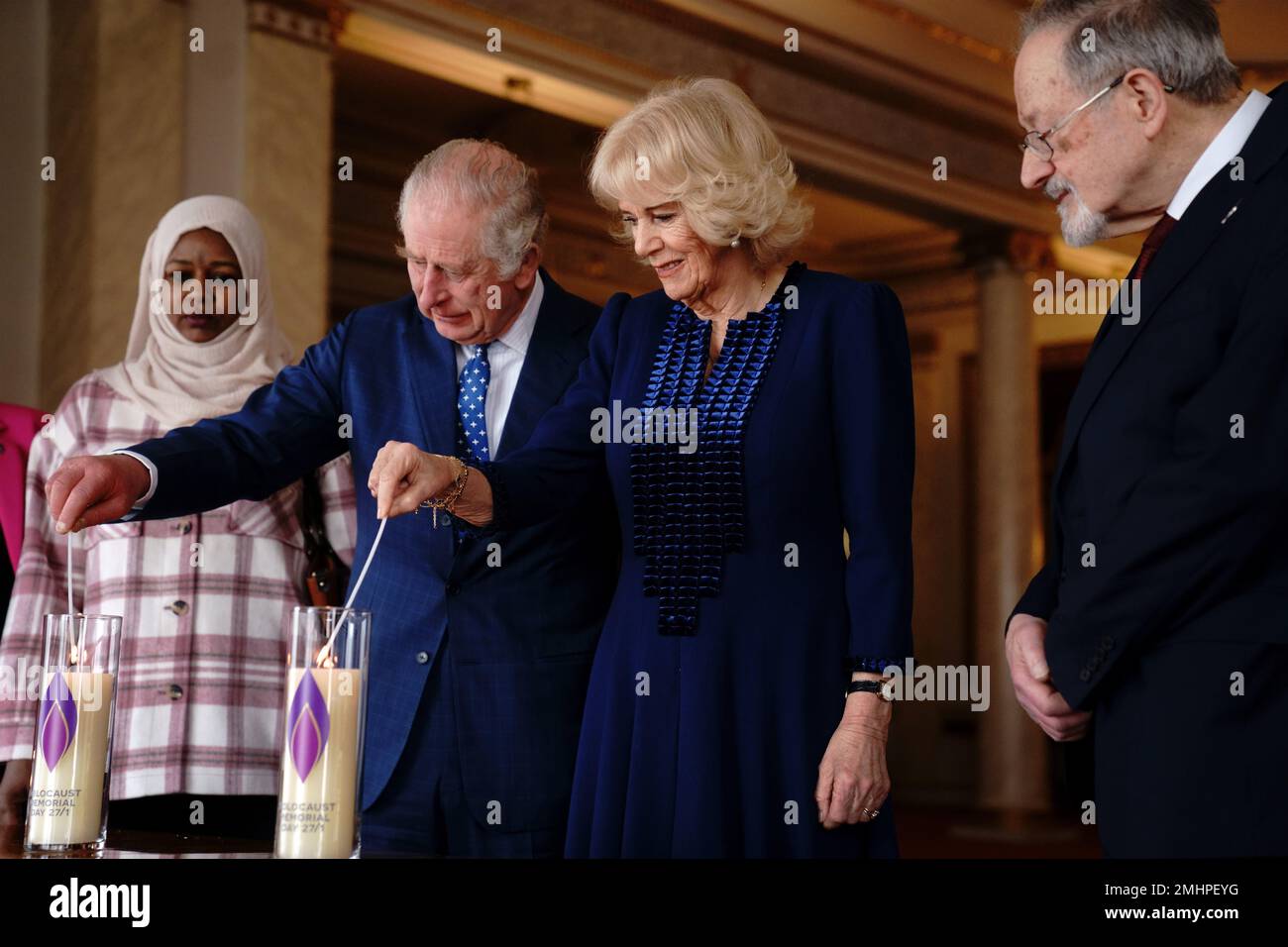 El rey Carlos III y la Reina consorte encienden una vela en el Palacio de Buckingham, Londres, para conmemorar el Día de los Caídos del Holocausto, junto al sobreviviente del Holocausto, el Dr. Martin Stern, y un sobreviviente del genocidio de Darfur, Amouna Adam. Fecha de la fotografía: Viernes 27 de enero de 2023. Foto de stock