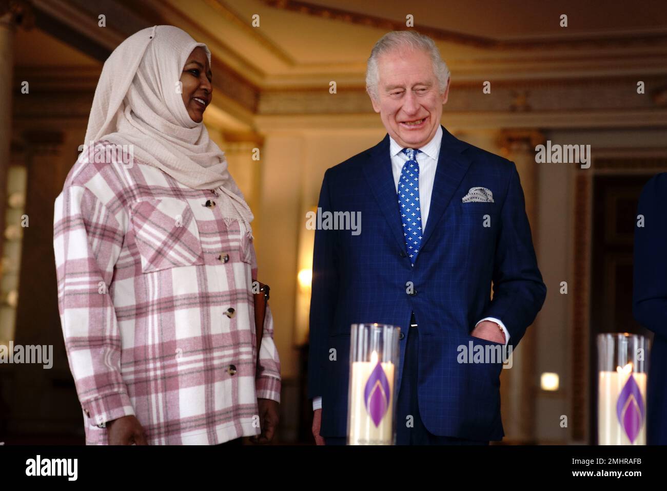 El rey Carlos III habla con Amouna Adamlight, sobreviviente del genocidio de Darfur, después de encender una vela para conmemorar el Día de los Caídos del Holocausto en el Palacio de Buckingham, Londres. Fecha de la fotografía: Viernes 27 de enero de 2023. Foto de stock