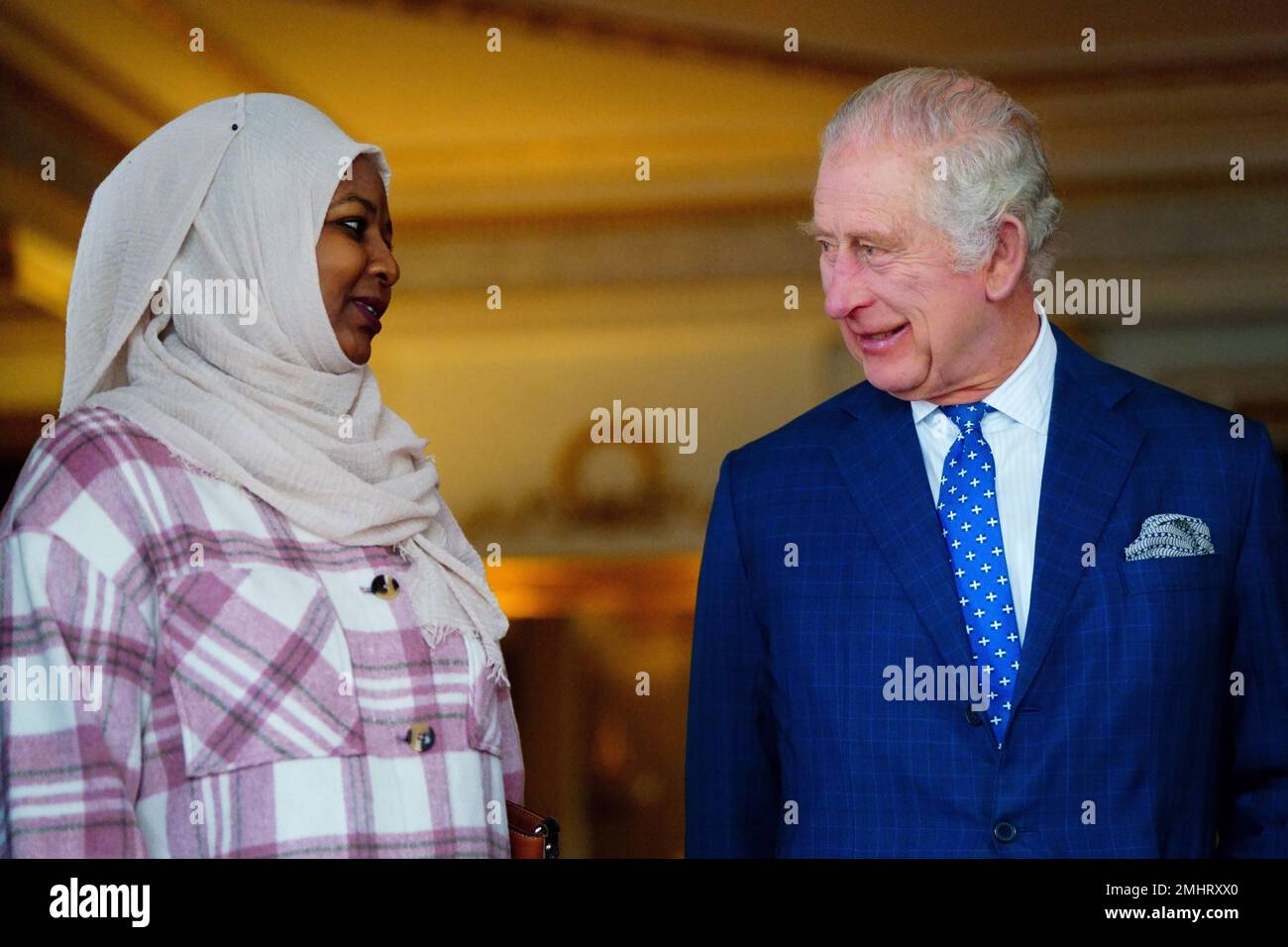 El rey Carlos III habla con Amouna Adamlight, sobreviviente del genocidio de Darfur, después de encender una vela para conmemorar el Día de los Caídos del Holocausto en el Palacio de Buckingham, Londres. Fecha de la fotografía: Viernes 27 de enero de 2023. Foto de stock