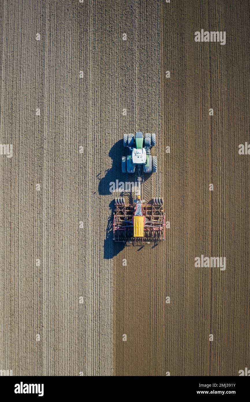 Vista aérea sobre tractor con sembradora neumática, máquina agrícola para siembra, trabajando en un campo en primavera Foto de stock