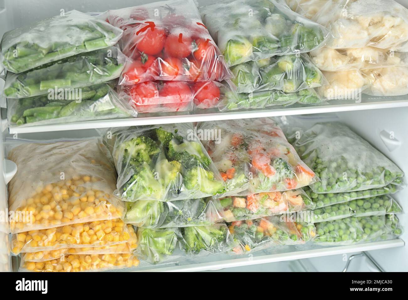 https://c8.alamy.com/compes/2mjca30/bolsas-de-plastico-con-diferentes-verduras-congeladas-en-el-refrigerador-2mjca30.jpg