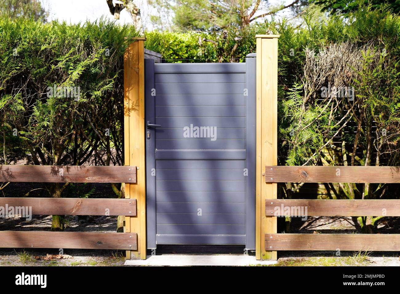 perder Minimizar Espinoso pequeña puerta gris de metal oscuro casa de aluminio con listones de madera  de acceso al jardín Fotografía de stock - Alamy