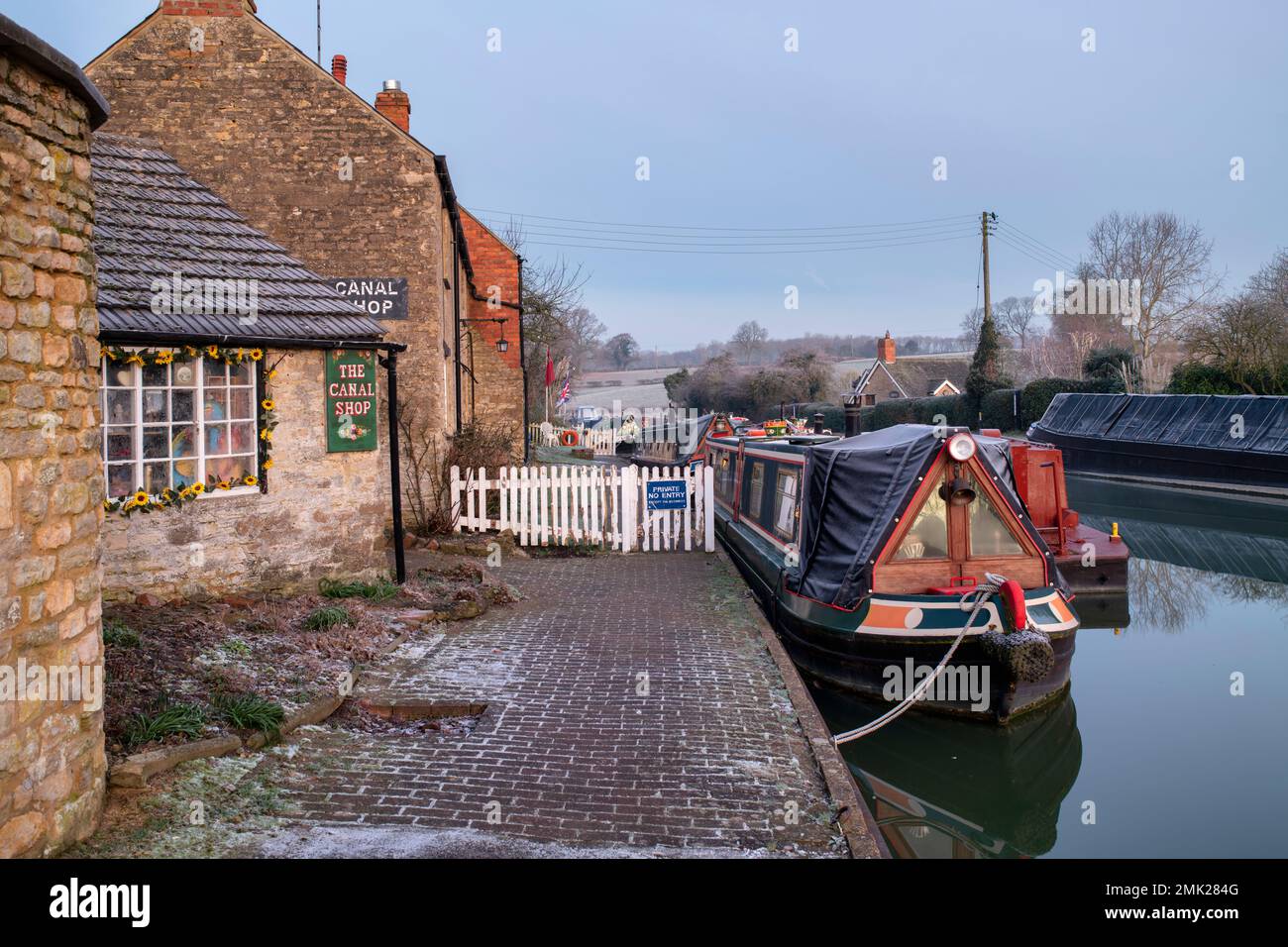 La tienda del canal y los barcos angostos en el Canal Grand Union en Stoke Bruerne en la helada de invierno al amanecer. Northamptonshire. Inglaterra Foto de stock