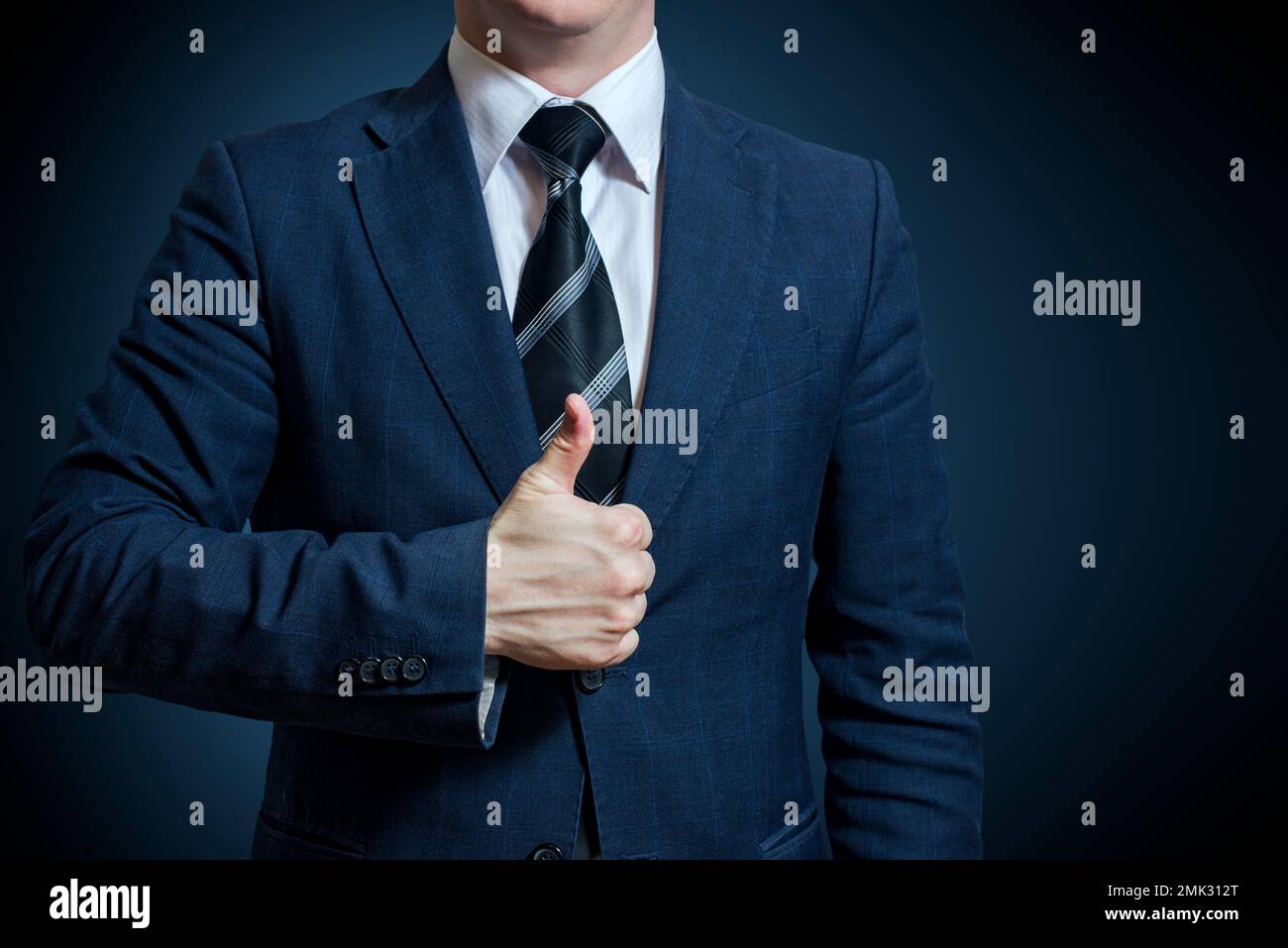Hombre de negocios en traje que muestra buena señal con su pulgar hacia arriba sobre fondo azul Foto de stock