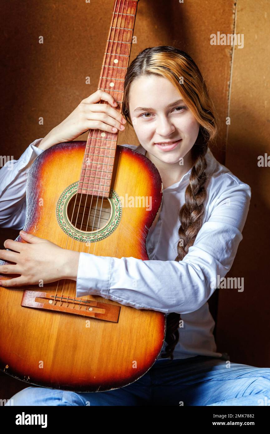 Joven mujer hipster sentada en el piso y tocando la guitarra en casa. Chica  adolescente aprendiendo a tocar la canción y escribiendo música en su  habitación. Afición, estilo de vida, relajarse, Instrumento,