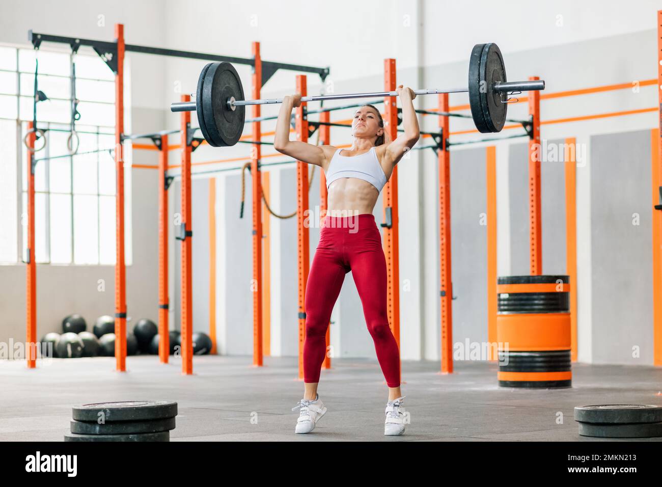 Levantador de pesas femenino fuerte de cuerpo completo en leggings y  sujetador haciendo ejercicio de prensa de empuje con barra pesada durante  el entrenamiento funcional durante el día en el gimnasio Fotografía
