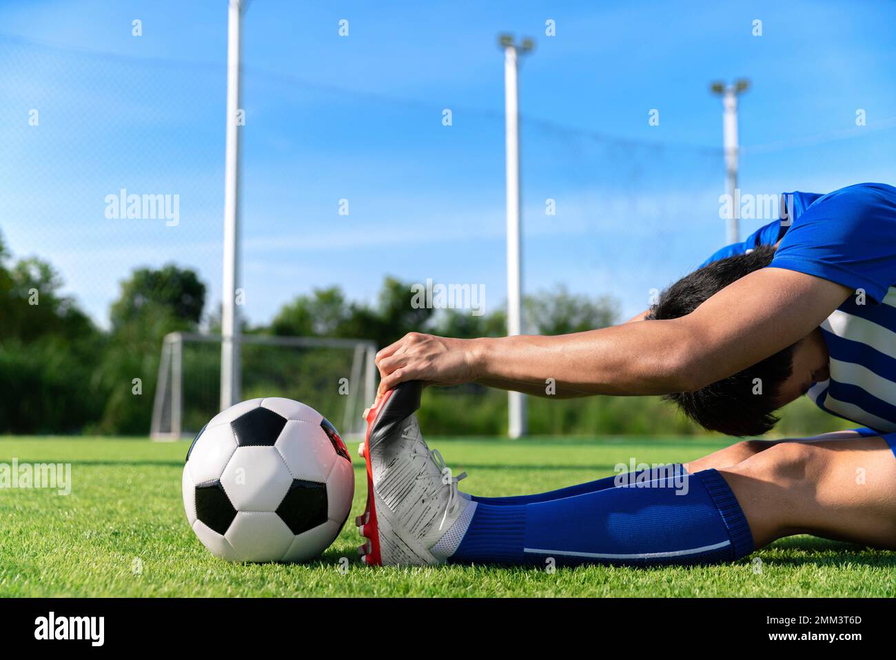 jugador de fútbol de fútbol que se estira durante el calentamiento antes de  la pelota de patada en la liga del partido en el estadio con el concepto  sano del deporte Fotografía
