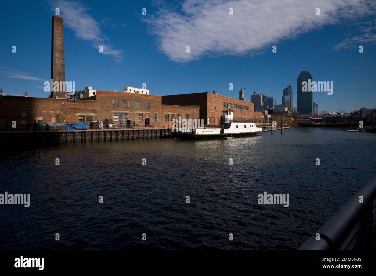 A rusting ferryboat is docked next to an aging industrial warehouse on