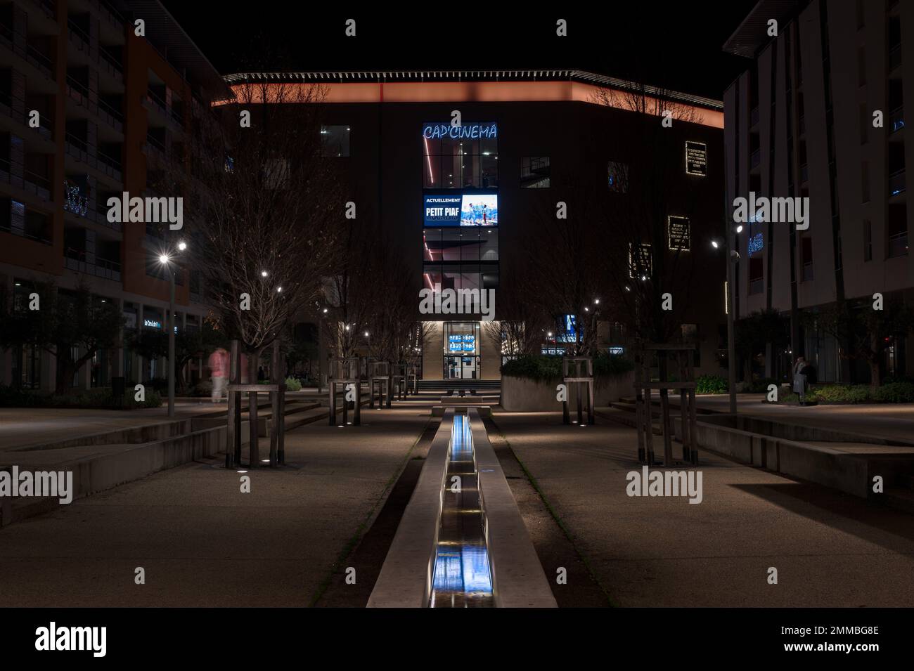 Nimes, Occitanie, Francia, 12 31 2022 - Escena nocturna iluminada de una plaza y una fuente detrás de la estación de tren Foto de stock
