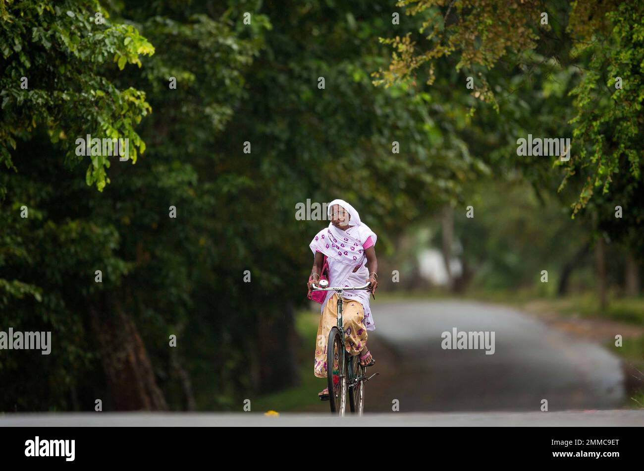 An Assamese woman in traditional attire rides a bicycle in Kaziranga