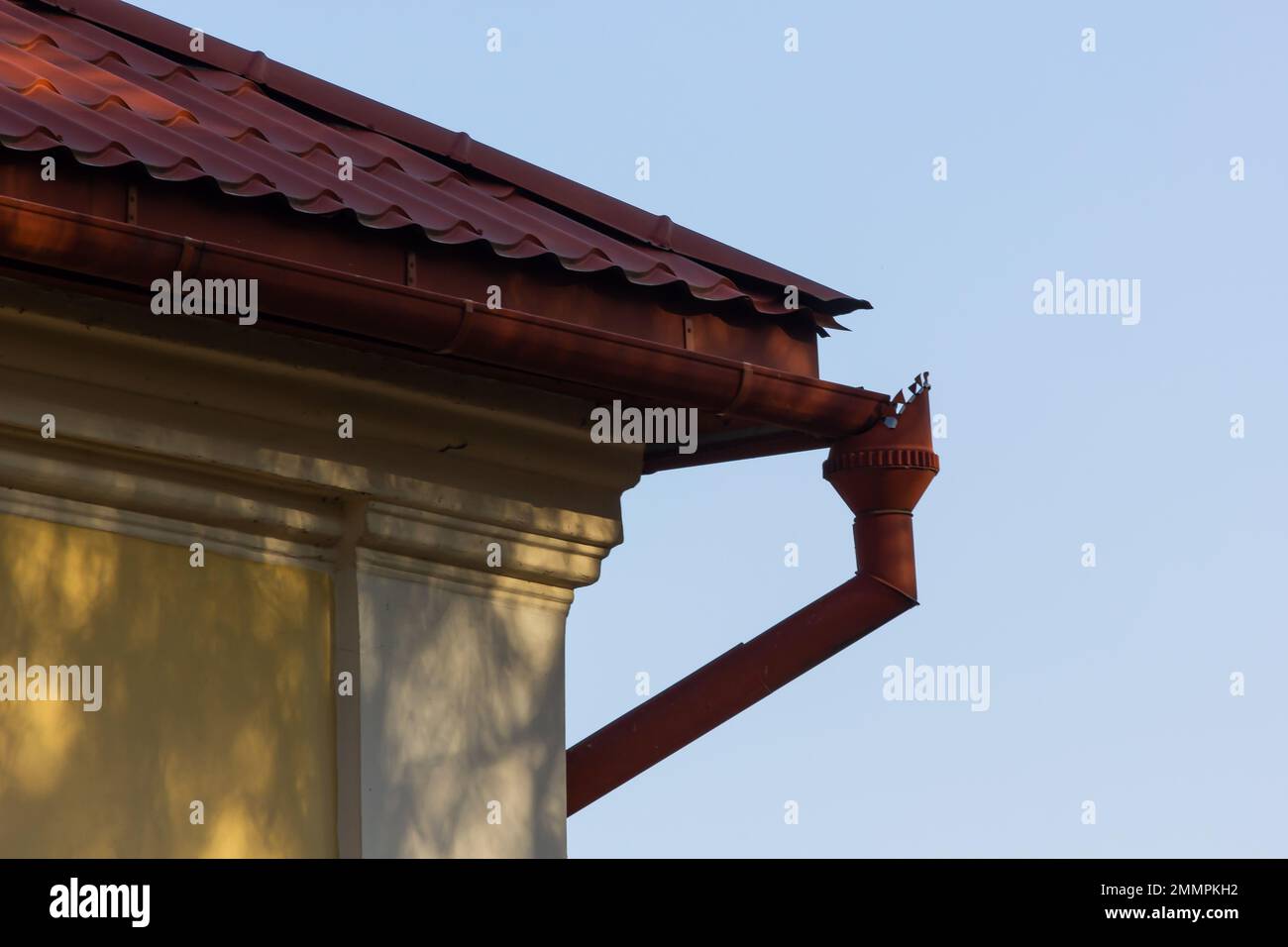 El techo de la casa está hecho de azulejos de metal rojo, una hermosa chimenea grande. Foto de stock