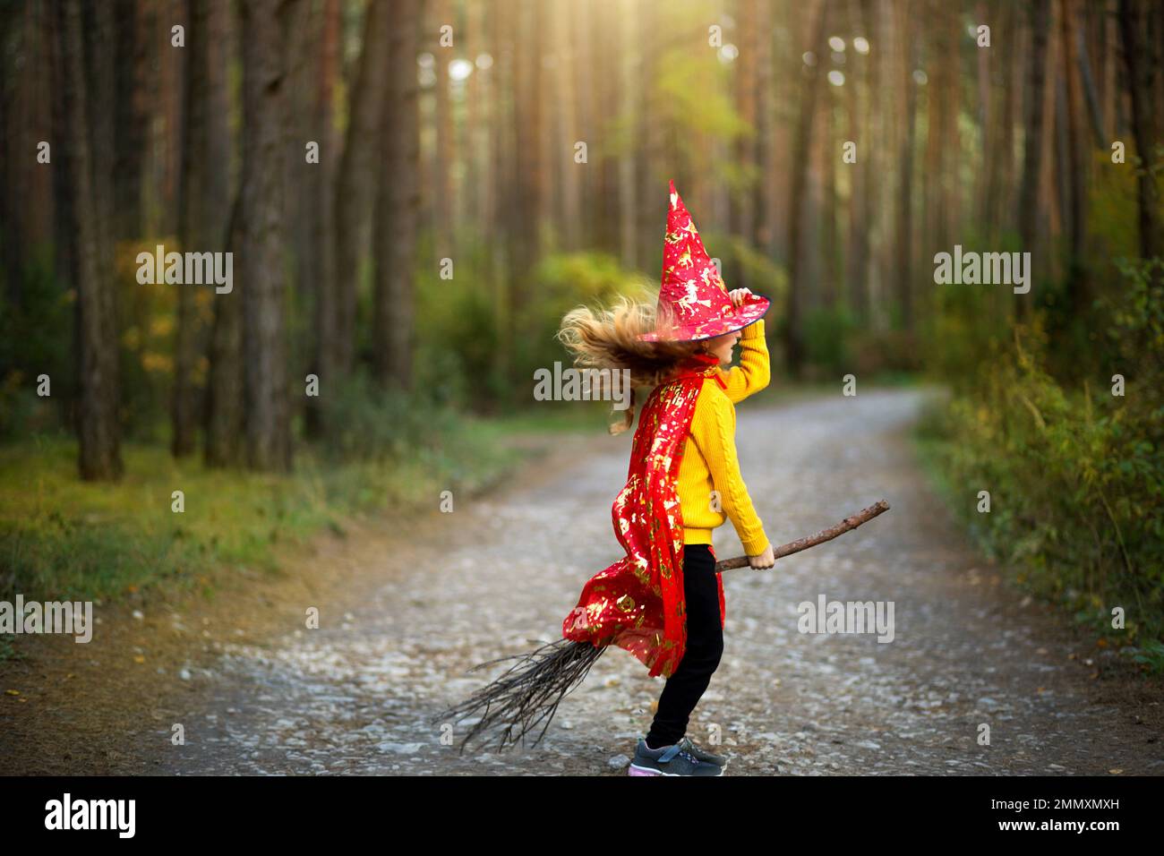 Una chica con un disfraz de bruja y sombrero en una escoba está jugando en  el bosque de otoño, yendo a una fiesta de Halloween Fotografía de stock -  Alamy