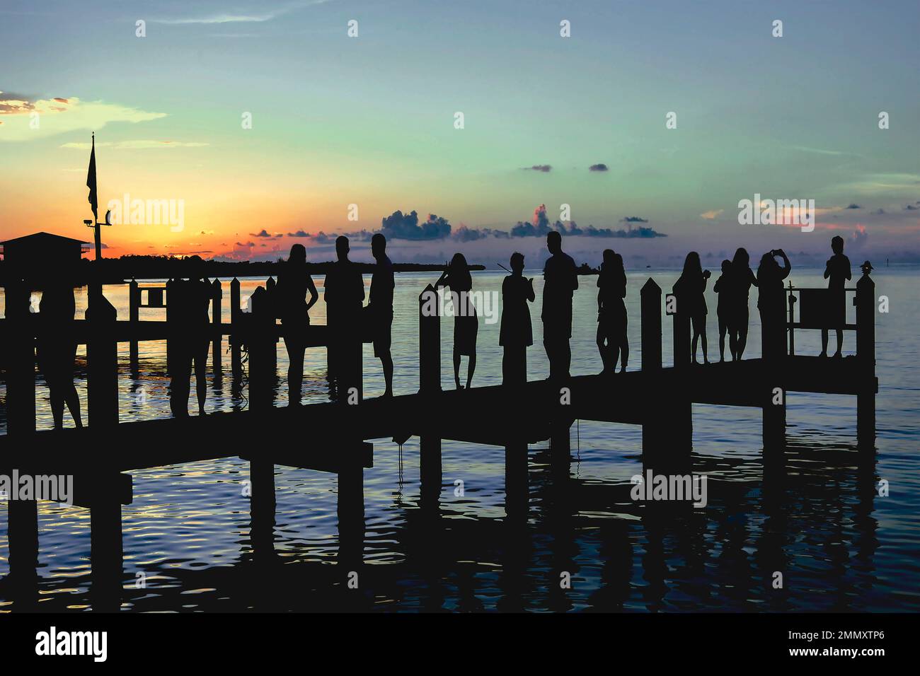 Silueta de la gente en el paseo marítimo después de la cena y cócteles viendo la puesta de sol en Marathon Key, FL en una hermosa noche de verano en agosto de 2017. Foto de stock
