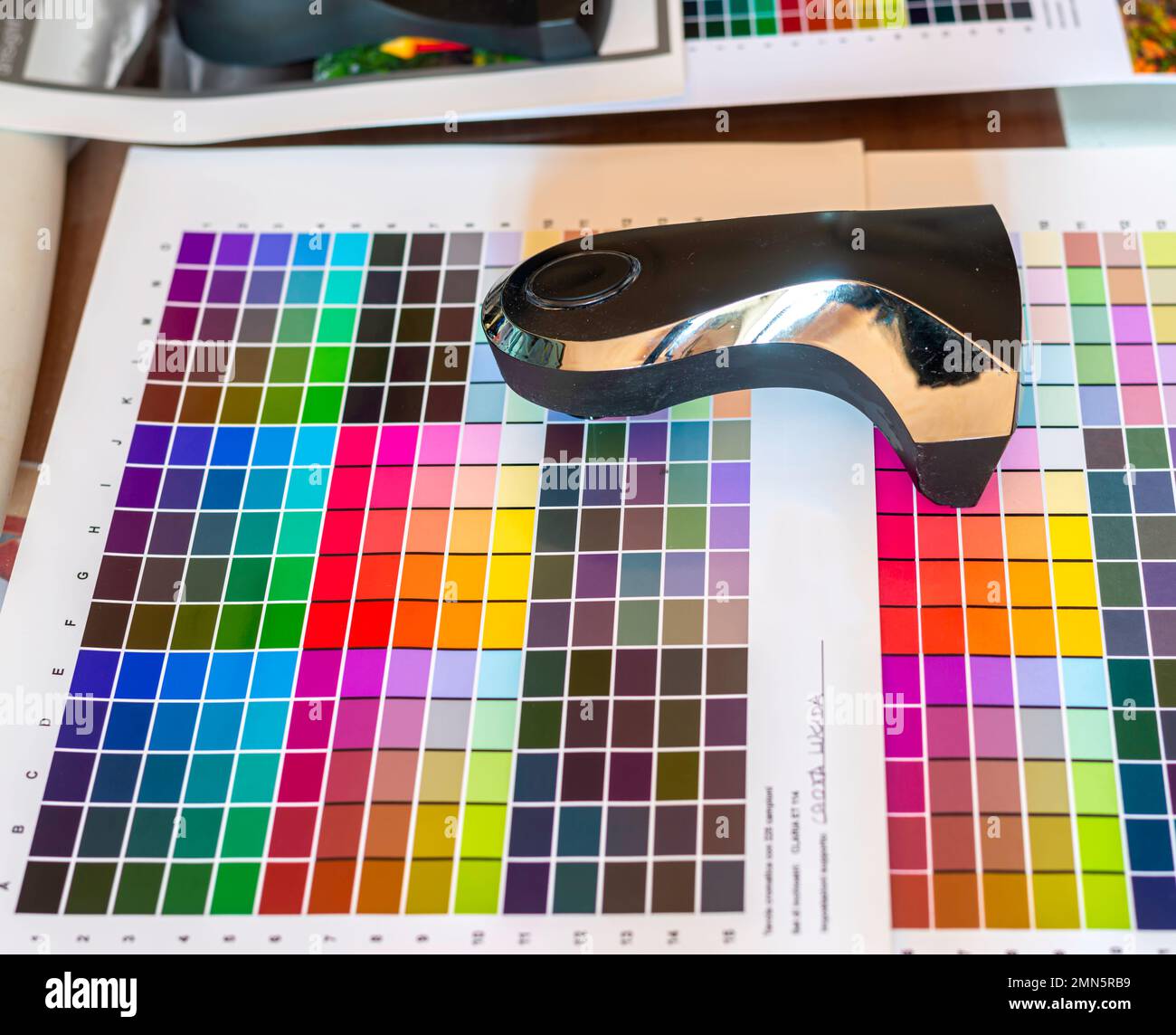 El técnico utiliza un espectrocolorímetro para leer parches con varios colores para la gestión del color relacionados con la creación de un perfil de color icc para la impresora Foto de stock