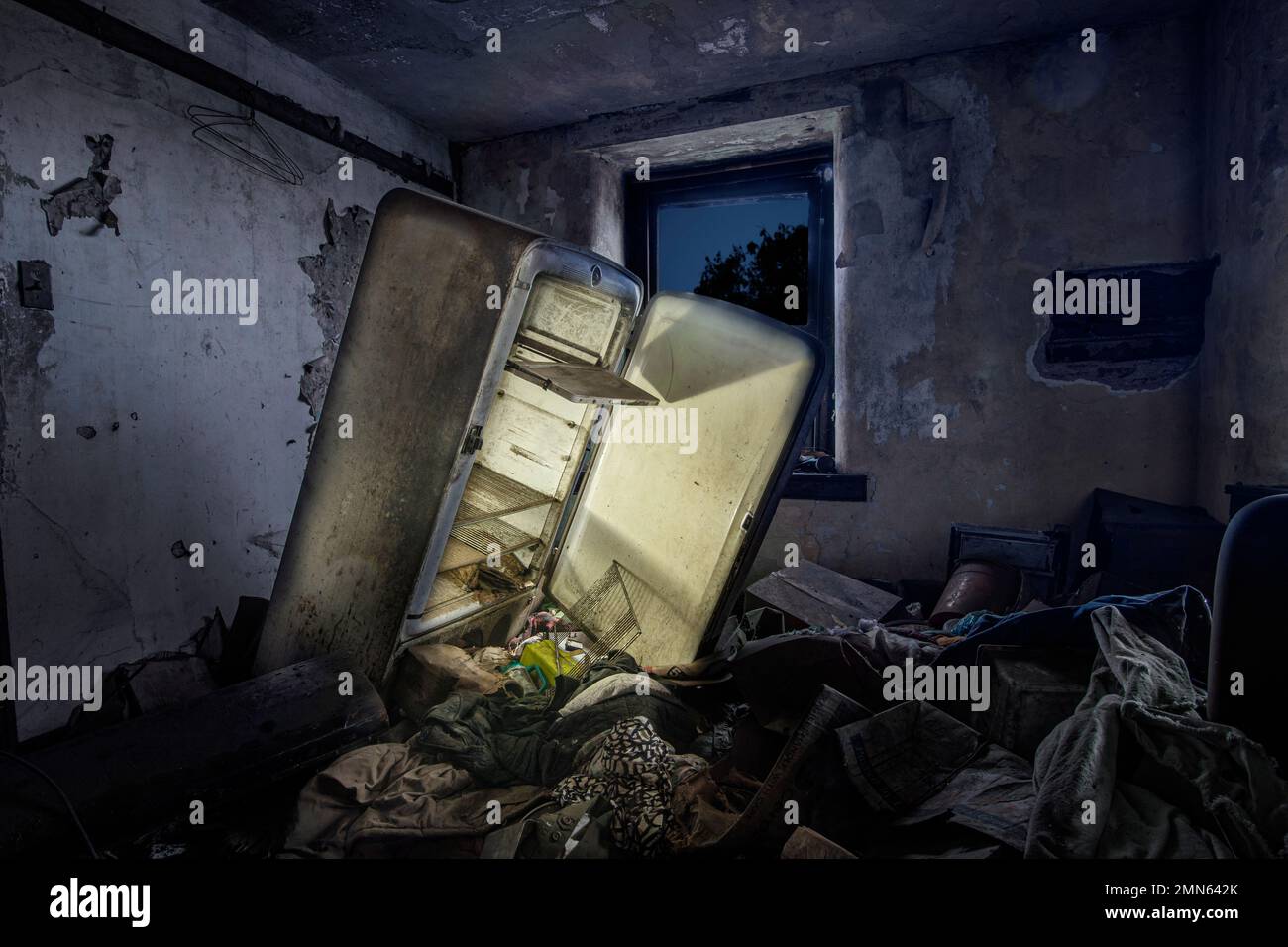 Refrigerador abandonado con luz brillando en la habitación llena de basura, Pennsylvania, EE.UU. Foto de stock