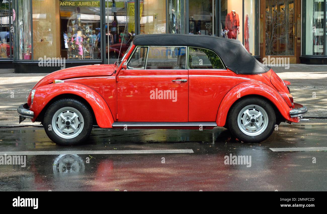 Un VW Beetle descapotable rojo se encuentra en el Kurfuerstendamm empapado por la lluvia en Berlín, Alemania Foto de stock