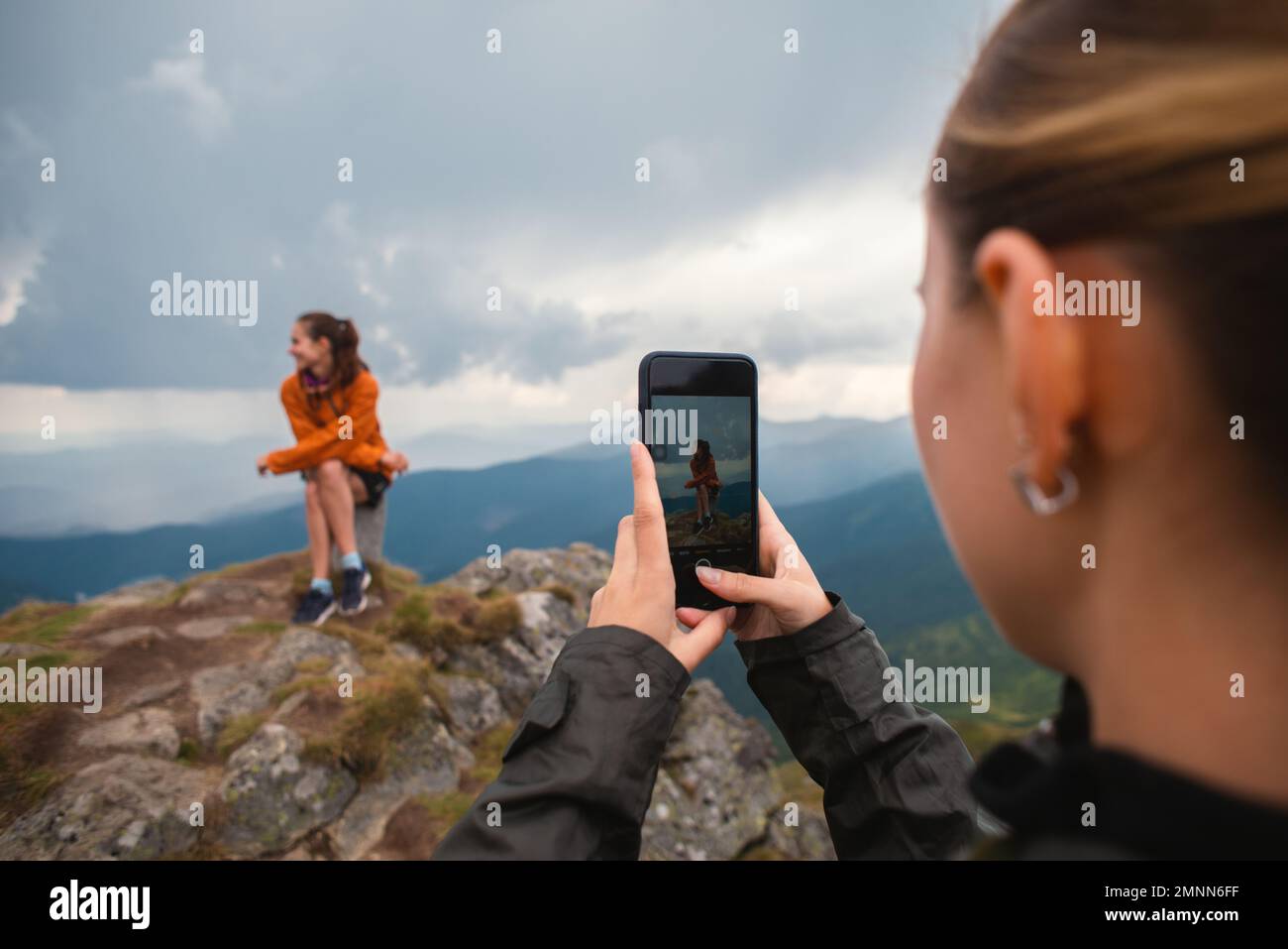 Dos amigos amigos jóvenes amigos excursionistas contra las montañas tomando una foto de un iphone en la naturaleza, Selfie teléfono inteligente moderno, usando el teléfono, amistad Foto de stock