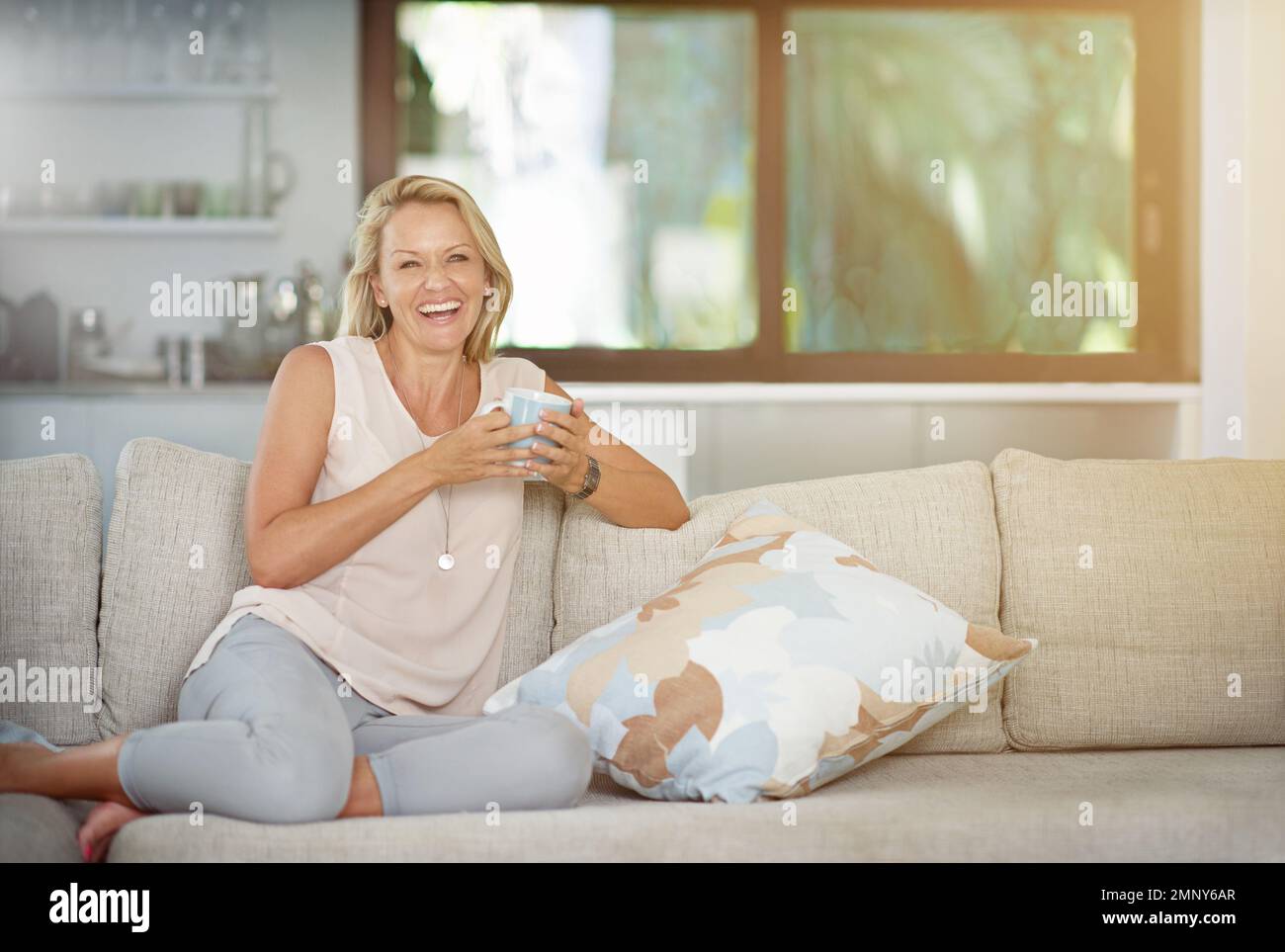 Ahora esto es lo que yo llamo vivir. Retrato de una mujer madura disfrutando de una bebida caliente mientras se relaja en el sofá en casa. Foto de stock