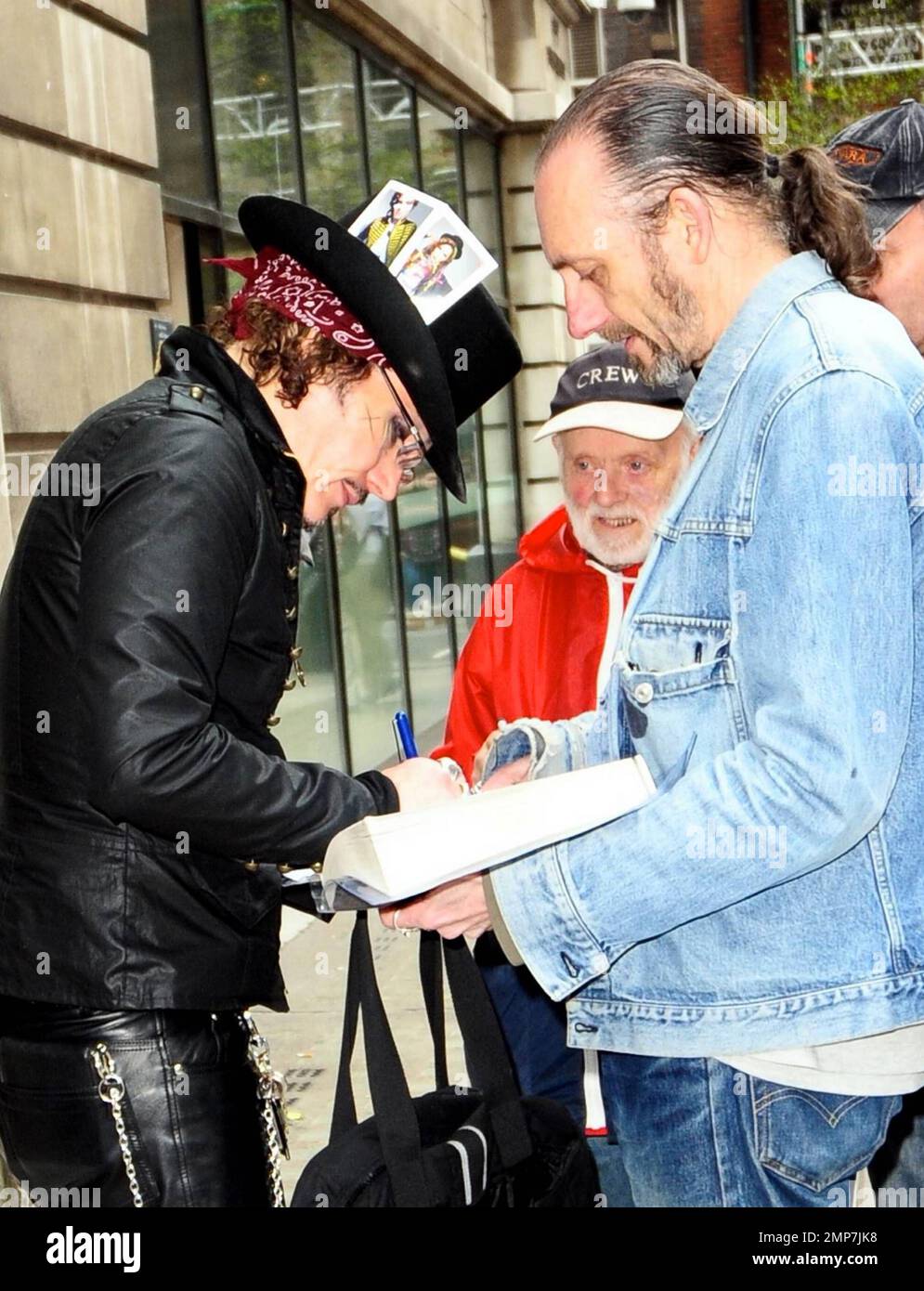 Con un atuendo completamente negro con un sombrero de copa acentuado con dos cartas, una de él y una de Boy el Adam Ant firma autógrafos para los fans cuando