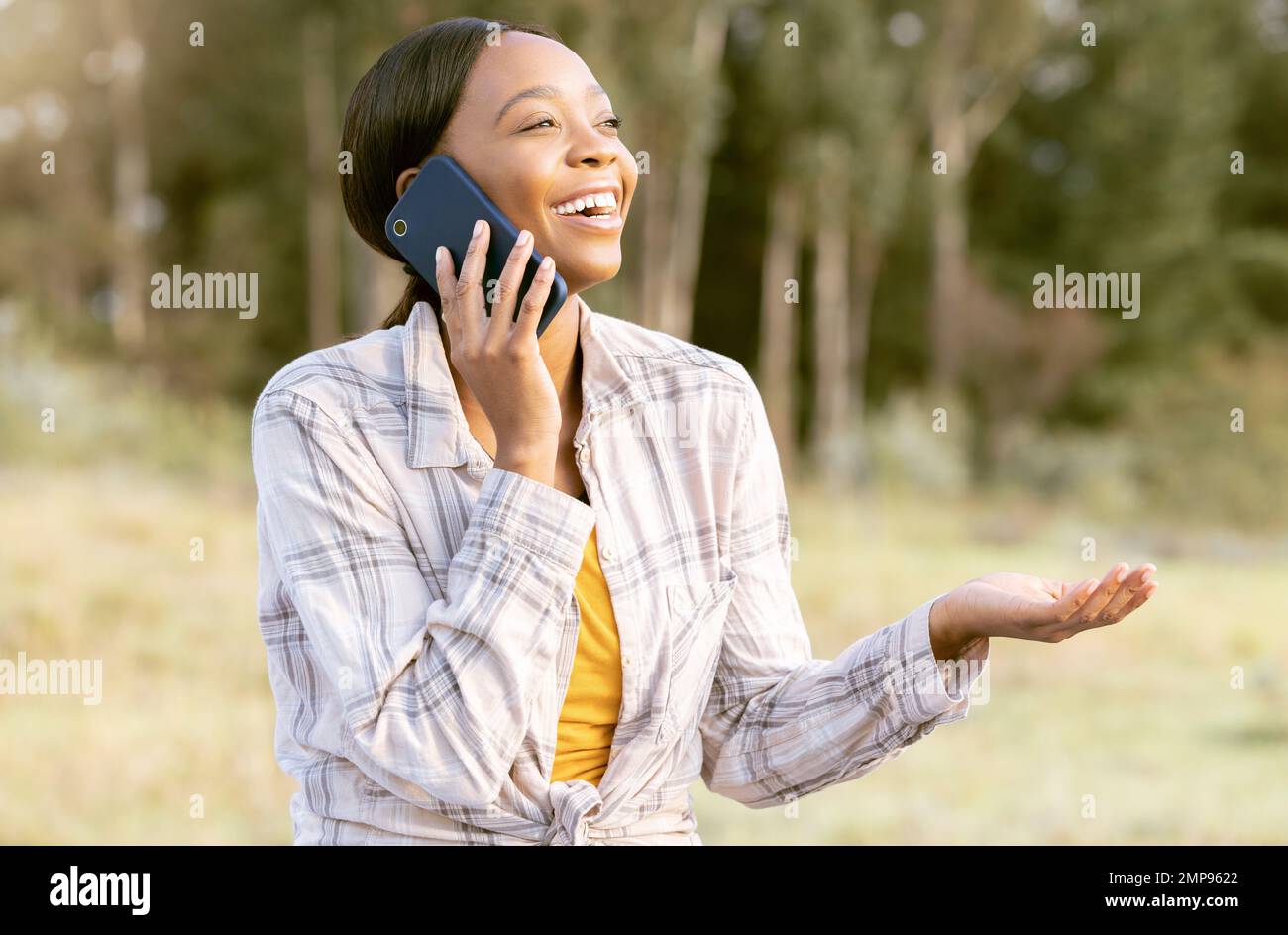 Mujer negra, maderas de la naturaleza y llamada telefónica feliz con pregunta, risa cómica y sonrisa en la hierba en verano. Aventura, conversación loca de smartphone o. Foto de stock