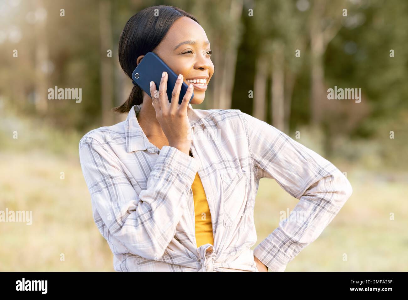 Mujer negra, bosque y llamada telefónica para hablar, pensar y sonreír en la hierba en sol de verano. Vacaciones de aventura, conversación cómica con smartphone o. Foto de stock