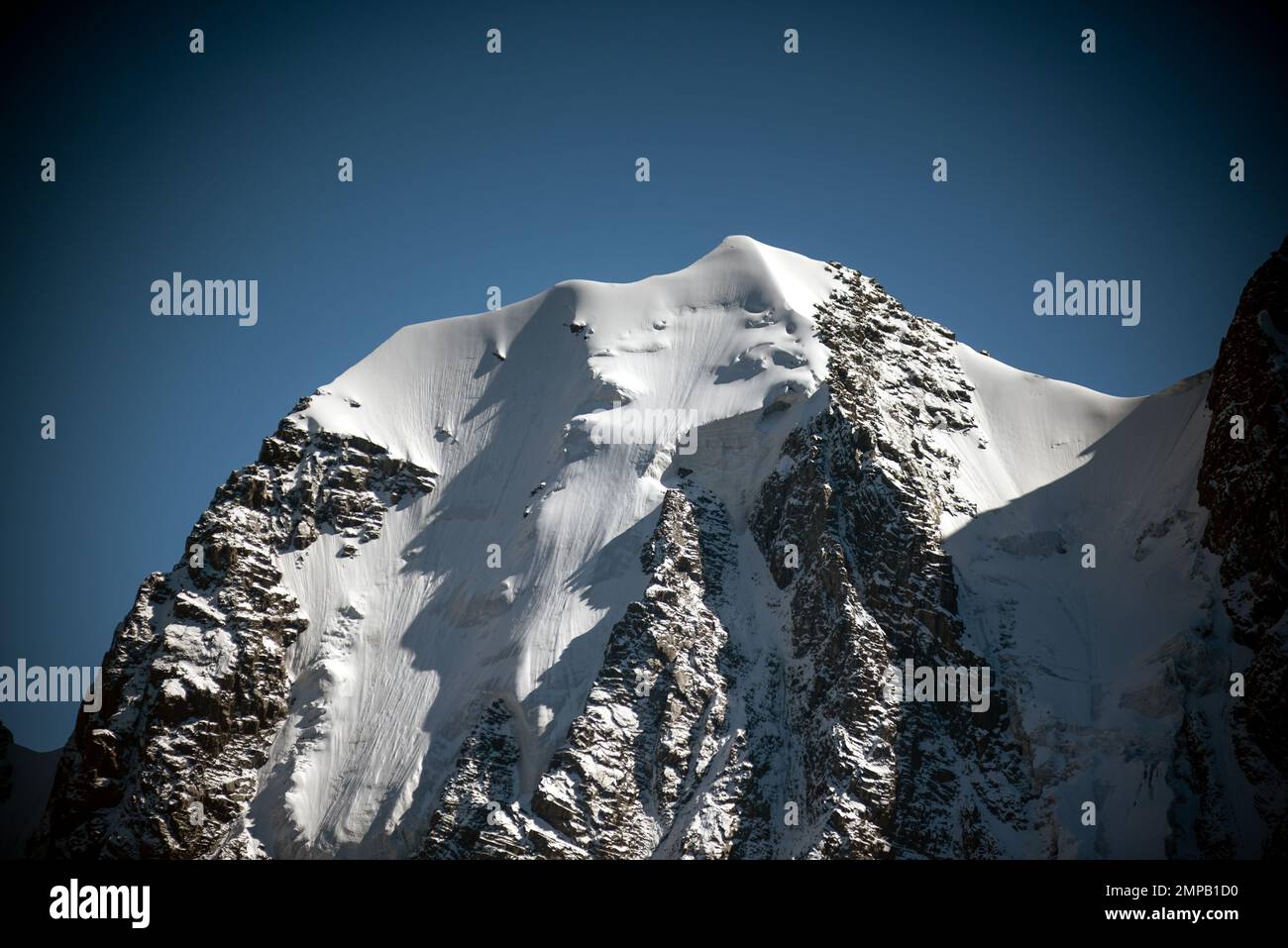 Panorama de la lengua de un glaciar alpino con nieve desciende de altos acantilados de piedra rocosa entre los picos en el Altai a la sombra. Top Skazka en t Foto de stock