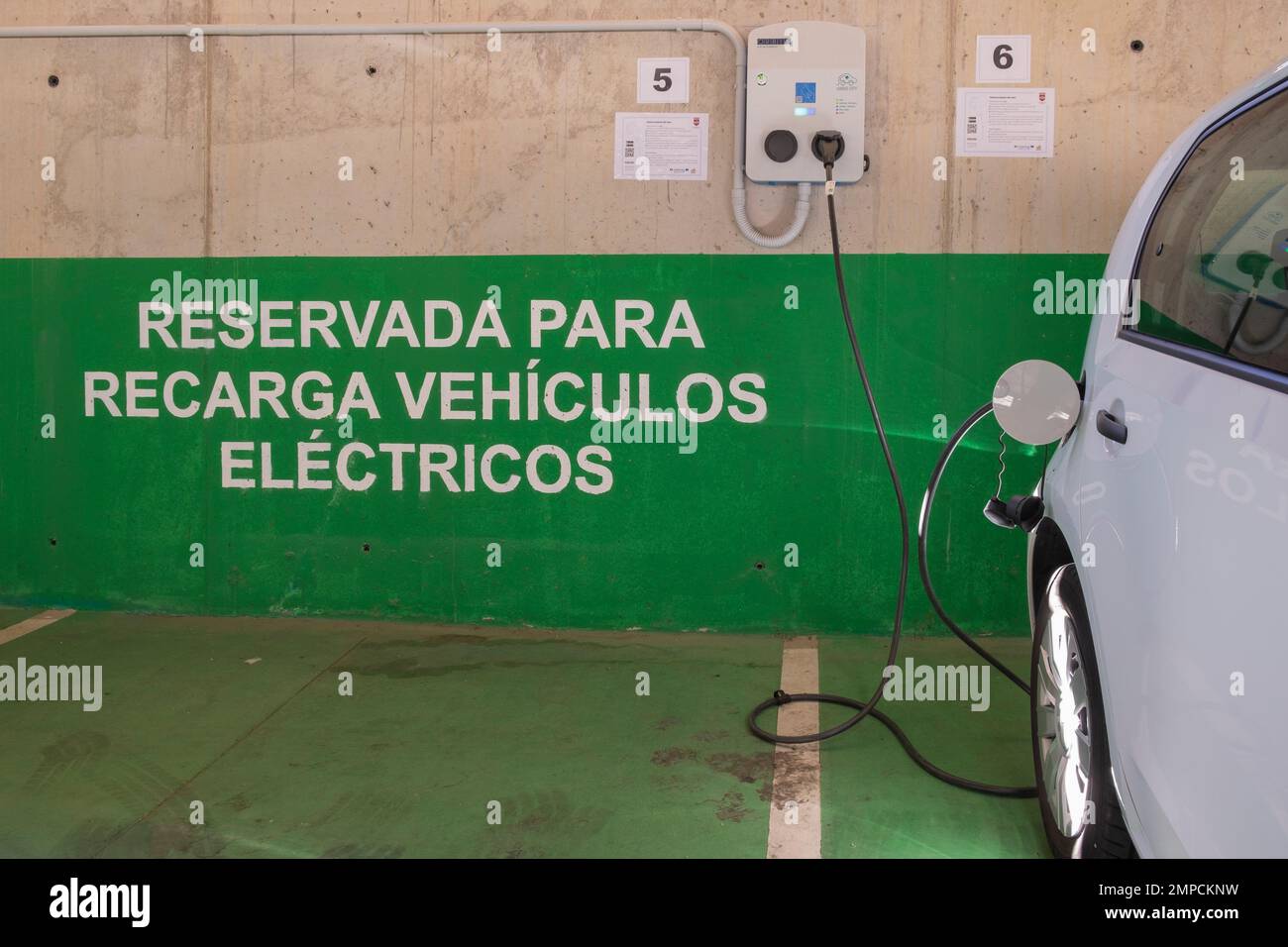 Plasencia, España - 29 de septiembre de 2022: Carga de vehículos eléctricos, carga de un coche eléctrico en garaje residencial, futuro del transporte Foto de stock