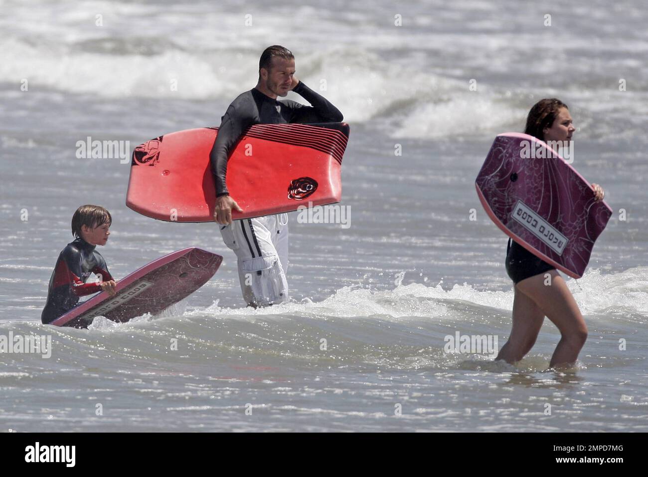David Beckham y la familia que usan tops de traje mojado se divierten en el  boogie boarding en el océano de California. Malibu, CA Julio 30 2011  Fotografía de stock - Alamy