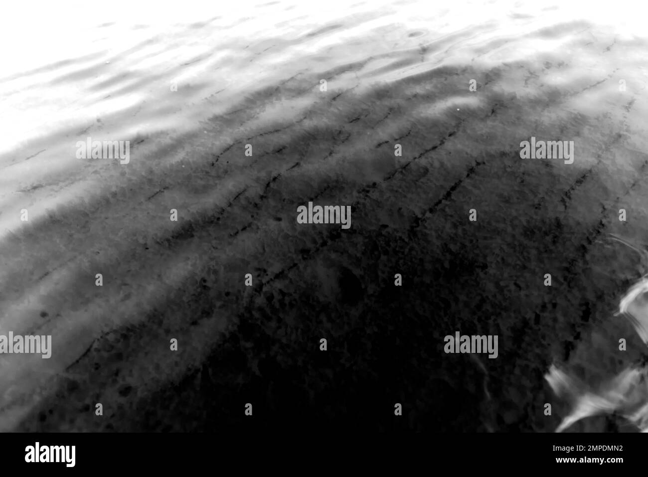 Foto abstracta en blanco y negro de la textura de la superficie de las ondas de agua transparente con arena en la parte inferior. Fondo Foto de stock