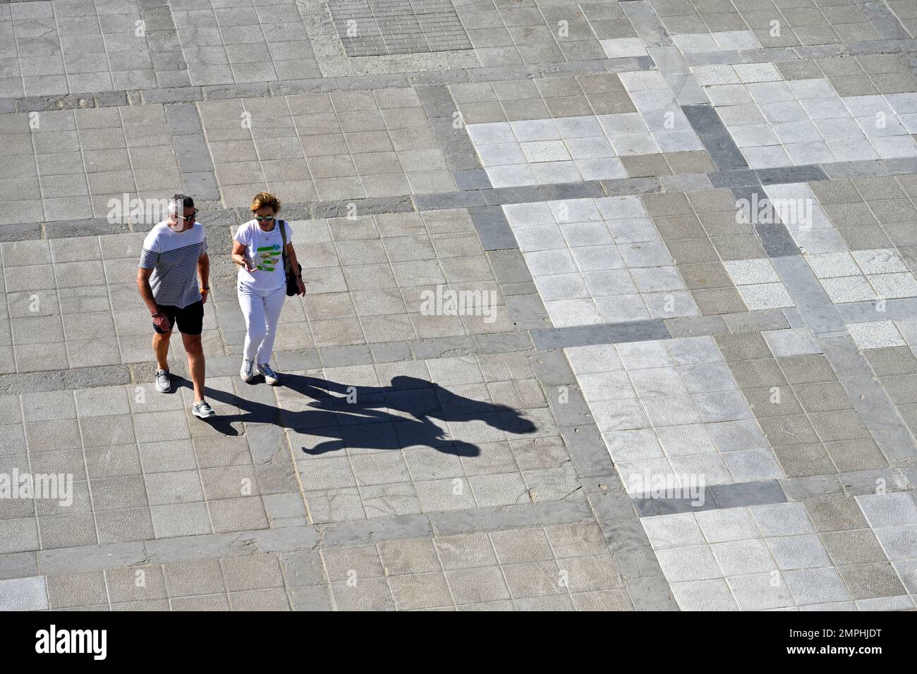 Vista desde arriba dos personas caminando en la plaza pública con sombras Foto de stock