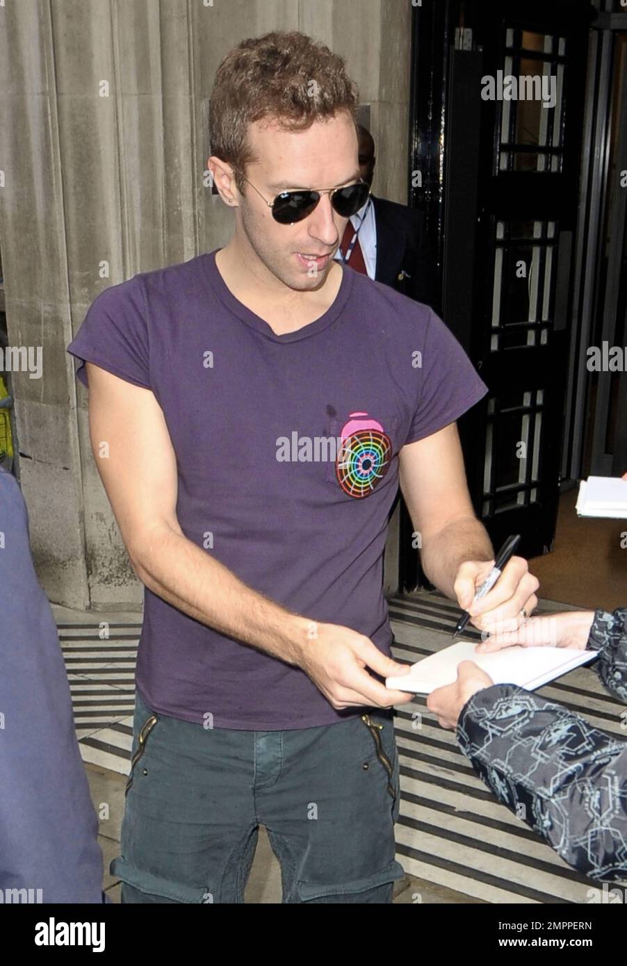 Chris Martin, líder de 'Coldplay', fue visto fuera de BBC Radio 2 con una  camiseta morada, pantalones grises, zapatillas blancas y gafas de sol.  Martin se tomó un tiempo para firmar autógrafos