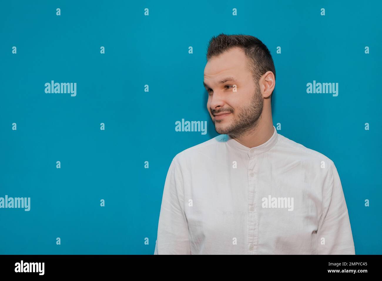 Tipo positivo y alegre Apariencia caucásica Empresario elegante en una camisa blanca sobre un fondo azul. Foto de stock