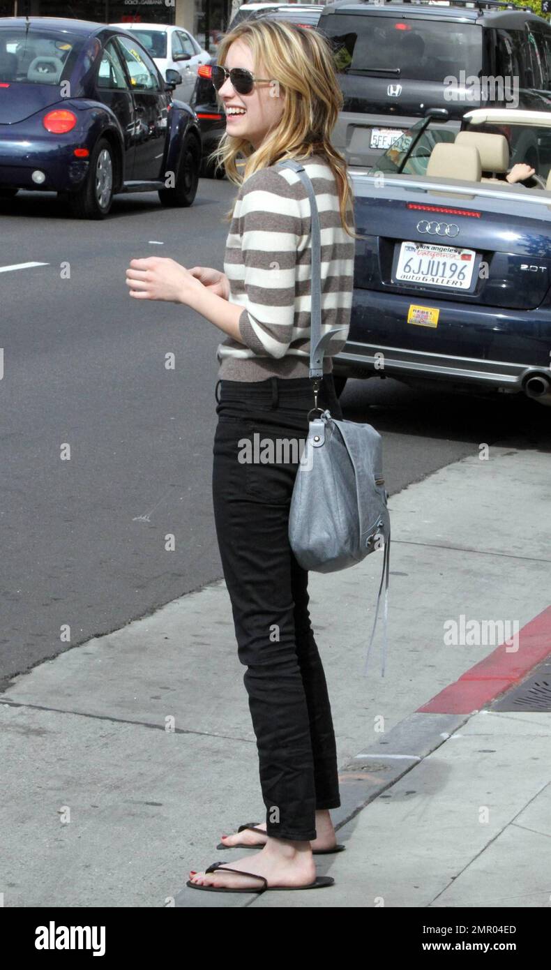 Con un top a rayas, jeans negros y sandalias de salón, la actriz Emma  Roberts saluda después de dejar una cita con un clavo en un salón local.  Roberts conversó en su