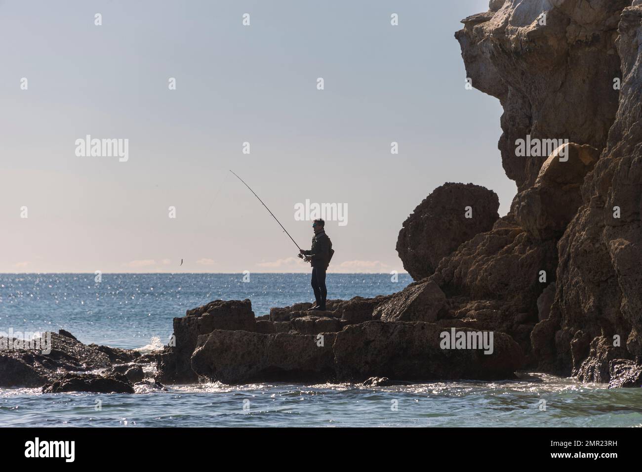 Hombre pescando desde las rocas. Foto de stock