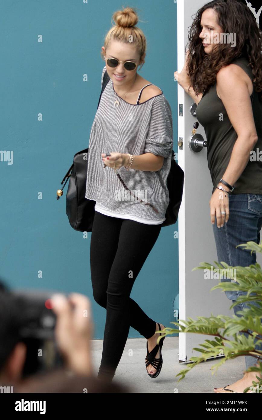 Miley Cyrus lleva un top de patrón gris con leggings negros y un gran bolso  negro mientras sale de su clase de pilates en Los Angeles, CA. 12th de  julio de 2012