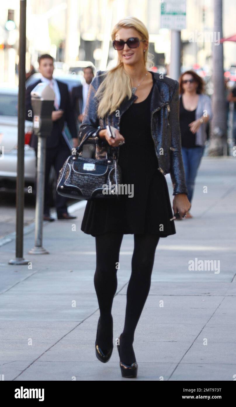 Paris Hilton en un vestido negro corto combinado con una chaqueta de cuero  negro, bolso negro, tacones de aguja negros y gafas de sol oscuras grandes  fue visto saliendo de un edificio