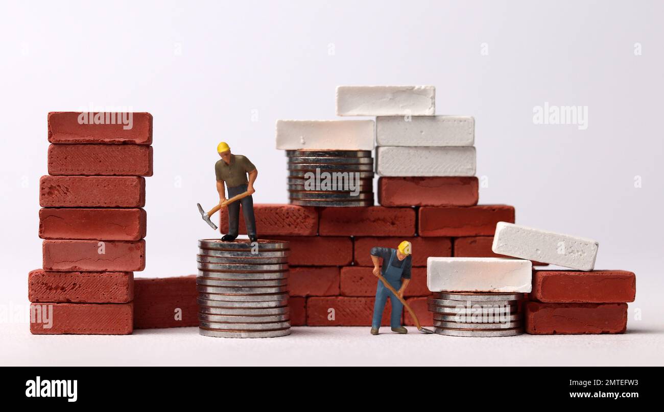 Trabajadores en miniatura construyendo ladrillos. Concepto de negocio con  monedas y personas en miniatura Fotografía de stock - Alamy