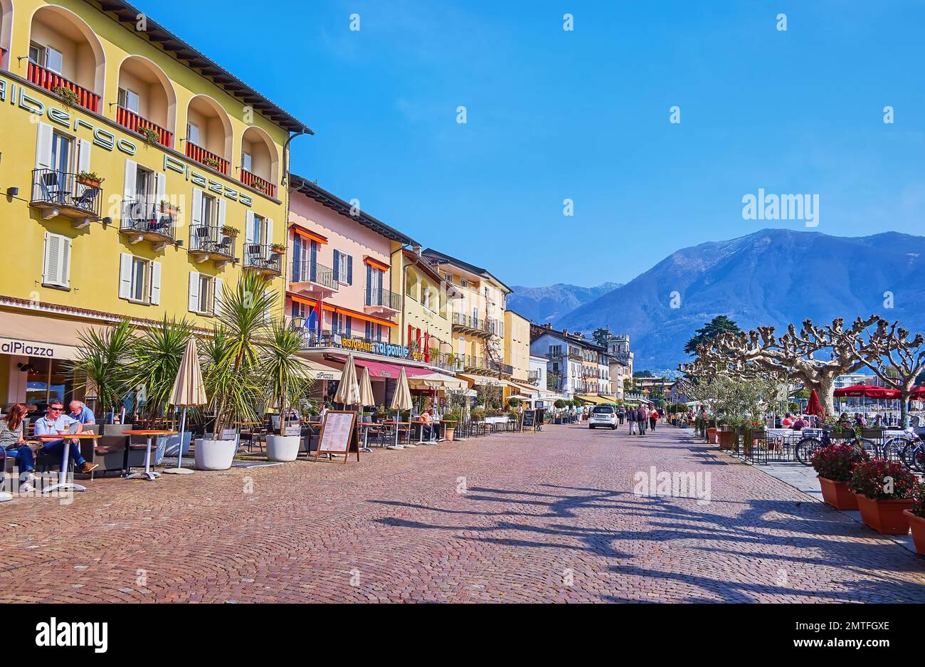 ASCONA, SUIZA - 28 DE MARZO de 2022: Piazza Giuseppe Motta es el paseo junto al lago con una línea de restaurantes turísticos al aire libre y casa histórica Foto de stock