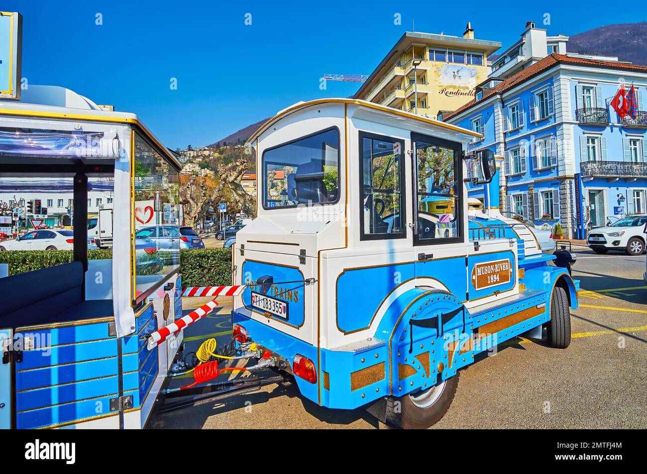 LOCARNO, SUIZA - 28 DE MARZO de 2022: El tren turístico azul brillante en el terraplén del lago Maggiore, el 28 de marzo en Locarno Foto de stock