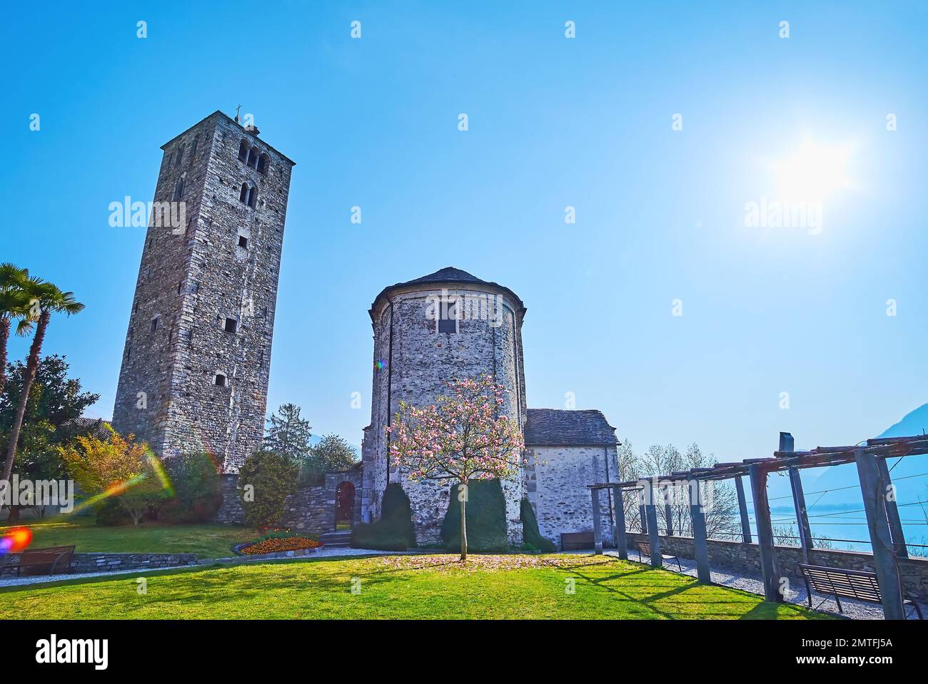 El brillante sol de la mañana brilla sobre el verde jardín de la iglesia de San Quirico, Locarno, Suiza Foto de stock