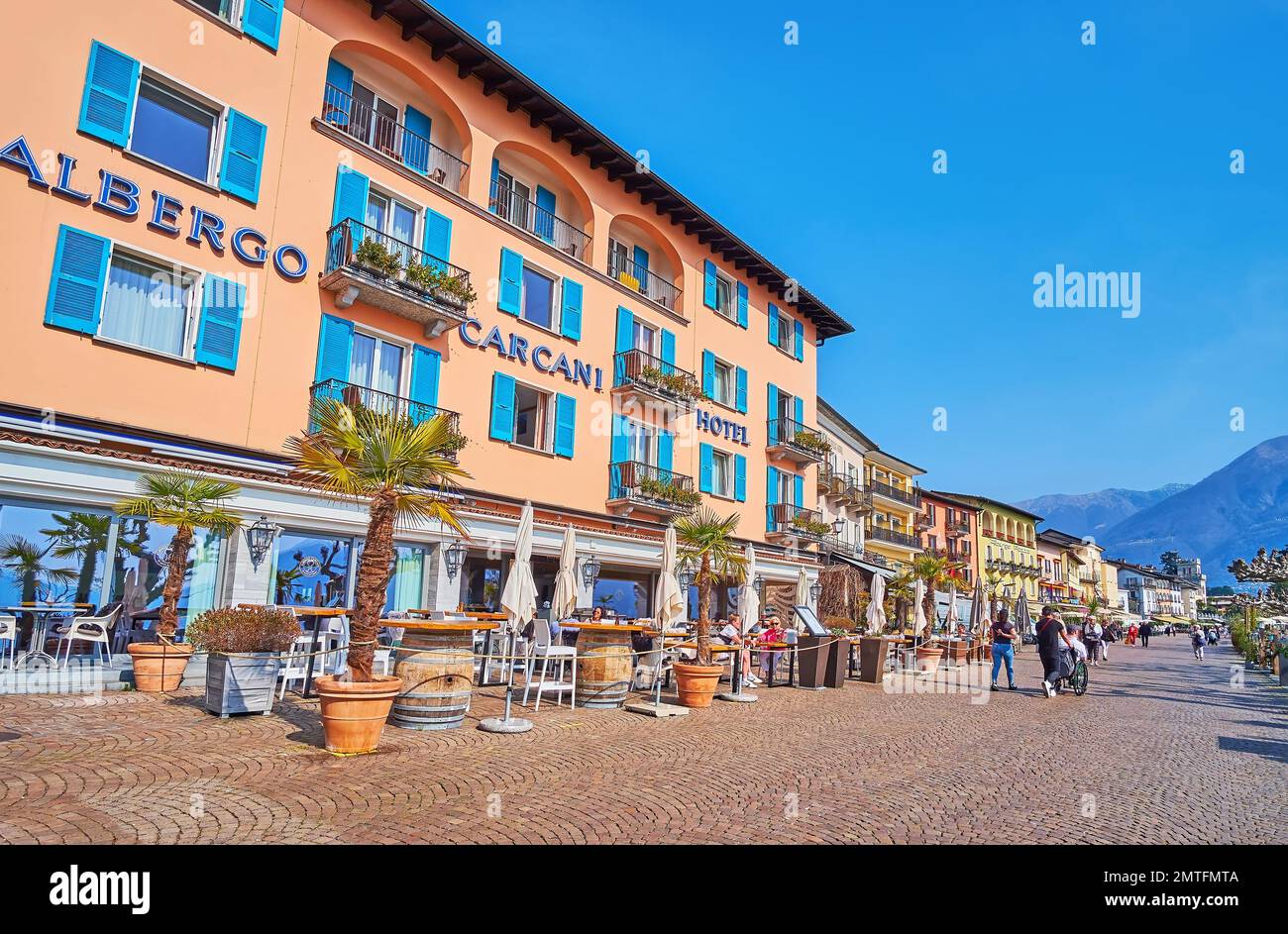 La línea de casas históricas, restaurantes al aire libre y bares en Piazza Giuseppe Motta - terraplén junto al lago en Ascona, Suiza Foto de stock